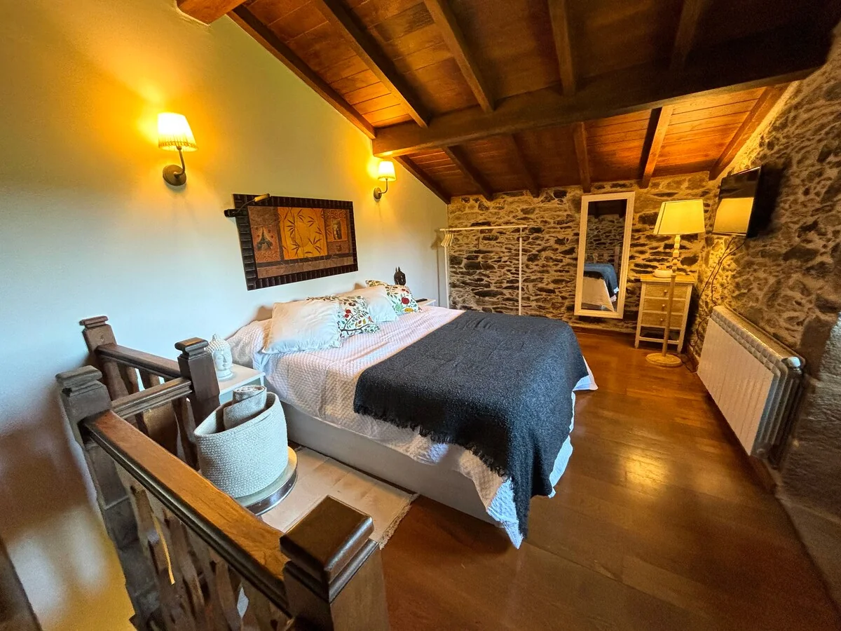 Attic bedroom of the F. de Castro apartment, with a double bed under wooden beams