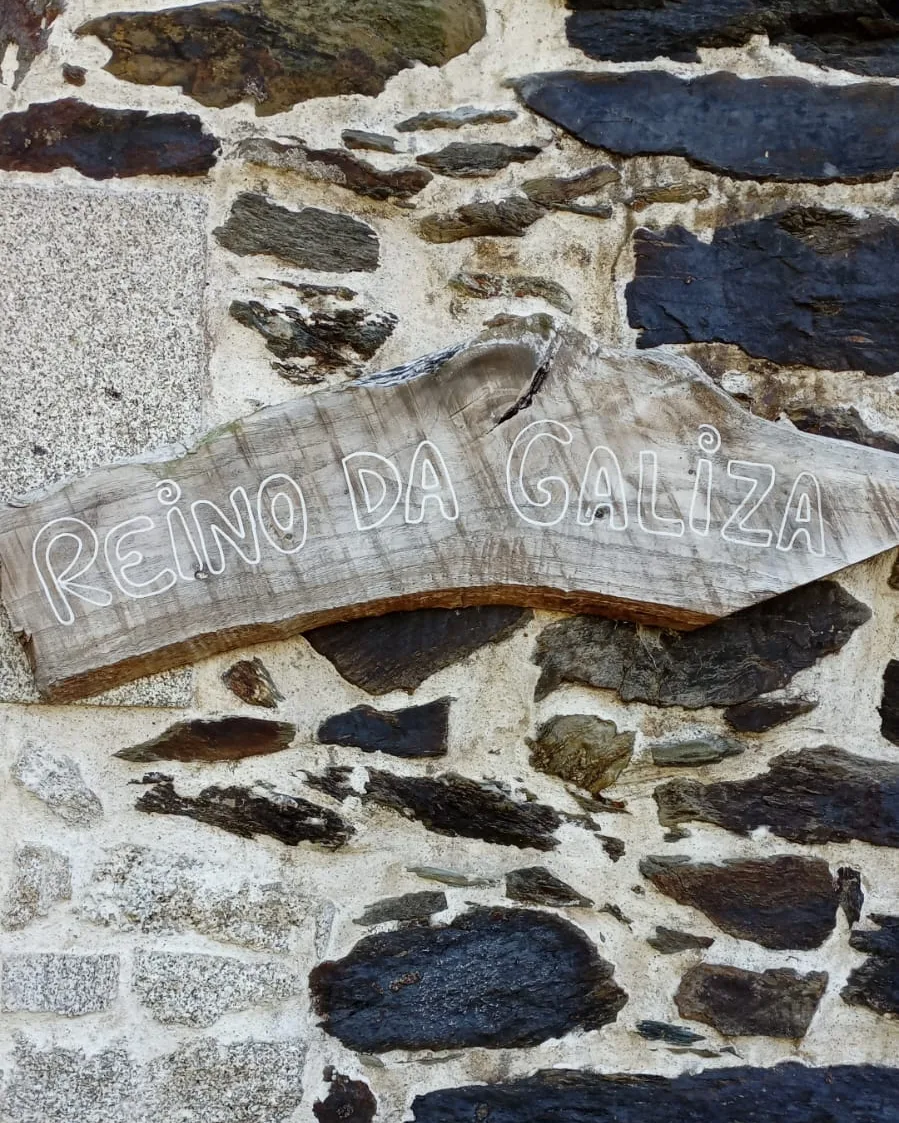 Wooden sign reading Reino da Galiza on a stone wall