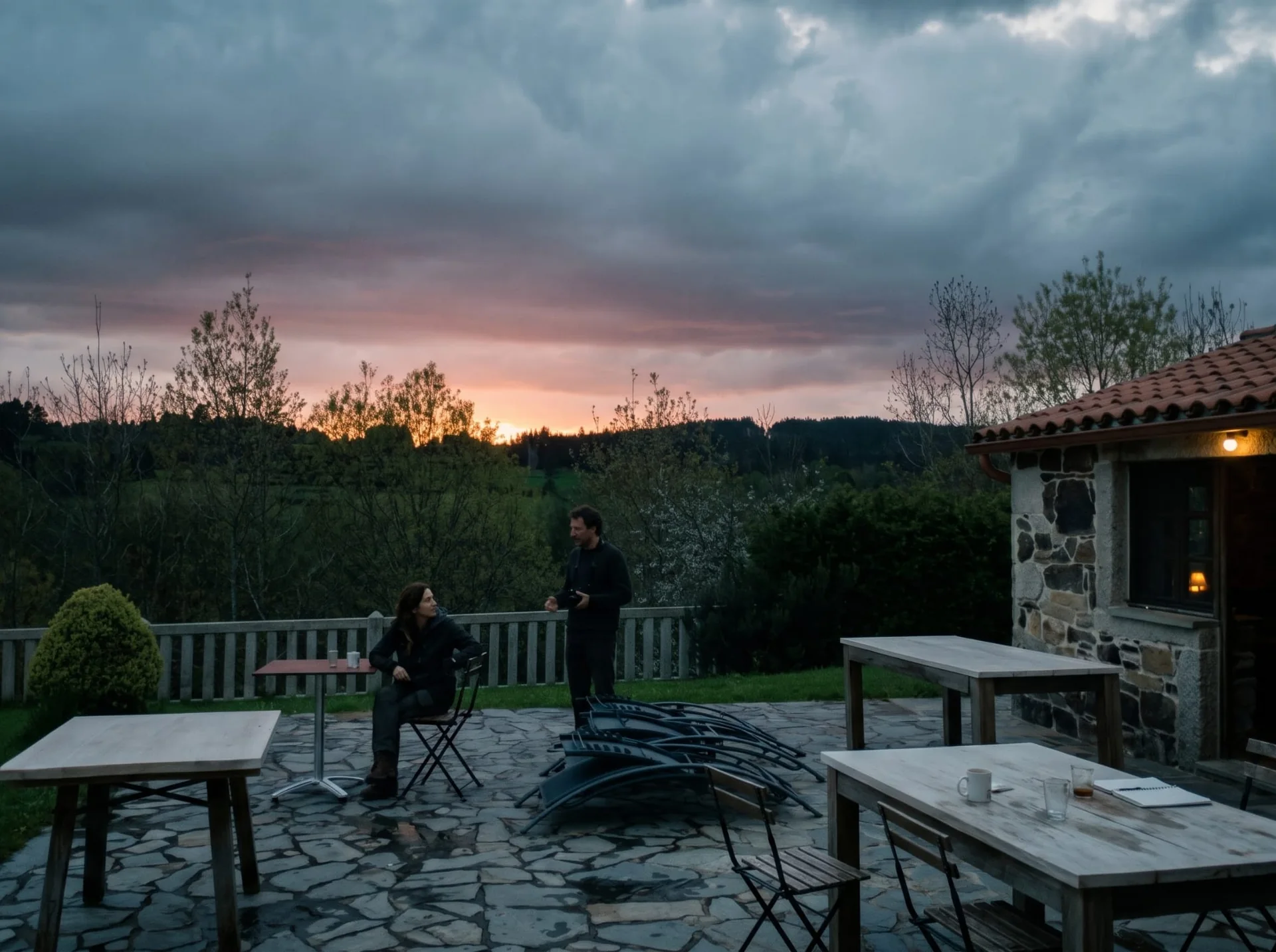 Two people chatting on the terrace at As Casiñas as the sun sets over Porto de Bois